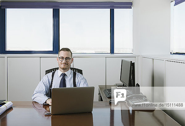 Porträt eines selbstbewussten Geschäftsmannes am Schreibtisch im Büro