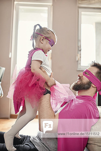 Vater und Tochter spielen Superheld und Superfrau und tun so,  als würden sie fliegen