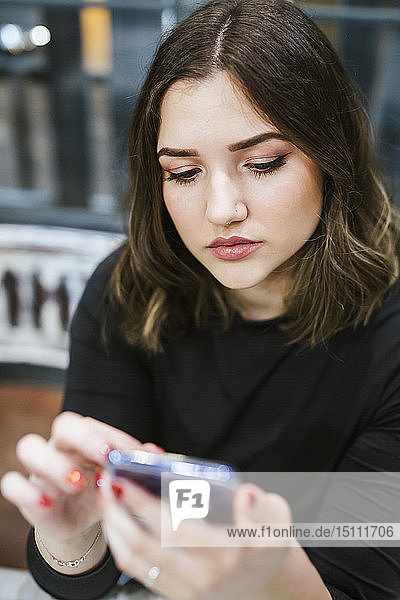 Porträt einer jungen Frau bei der Benutzung eines Mobiltelefons