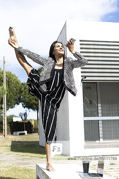 Balletttänzerin benutzt Smartphone vor einem Bürogebäude