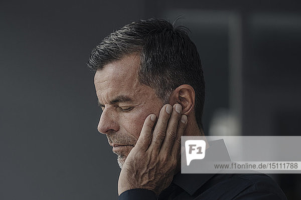Porträt eines reifen Geschäftsmannes mit Ohrenschmerzen