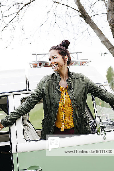 Laughing young woman leaning aout of wondow of her camper