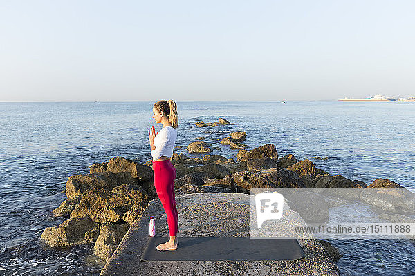 Junge Frau praktiziert Yoga am Strand  macht Gebetsposition