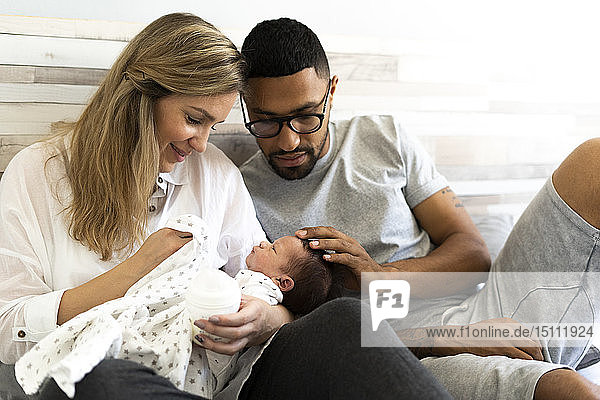 Happy father and mother with their newborn baby in bed