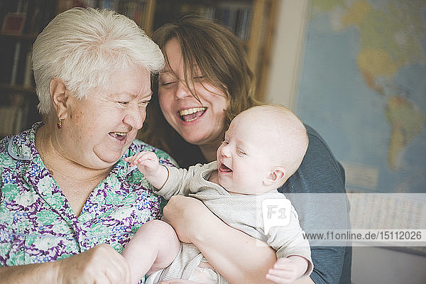 Glückliche Großmutter mit Mutter  die ein kleines Mädchen hält