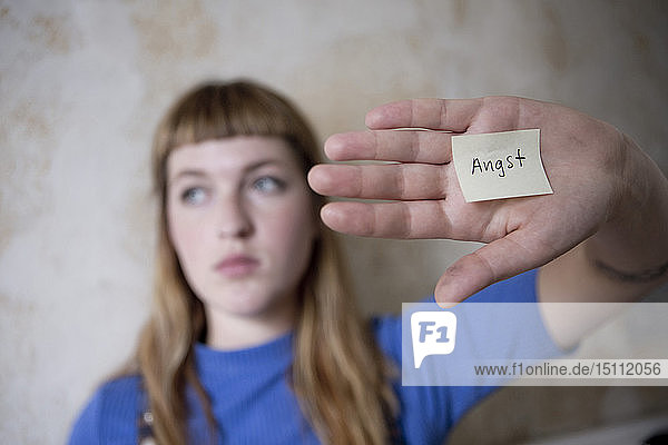 Studentin hält eine Hand vor die Augen  einen Zettel mit dem Wort Angst auf der Hand