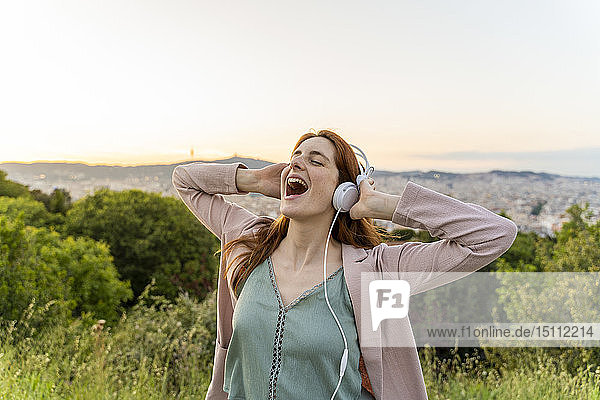 Junge rothaarige Frau mit Kopfhörern am Aussichtspunkt