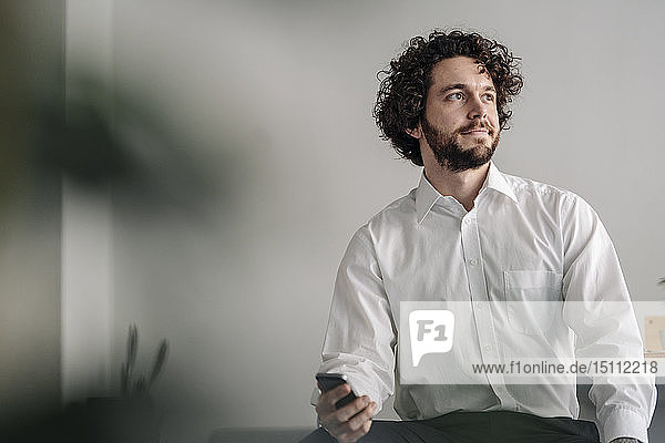Businessman with smartphone  looking away