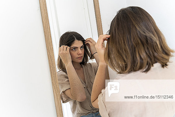 Brünette junge Frau beim Blick in den Spiegel