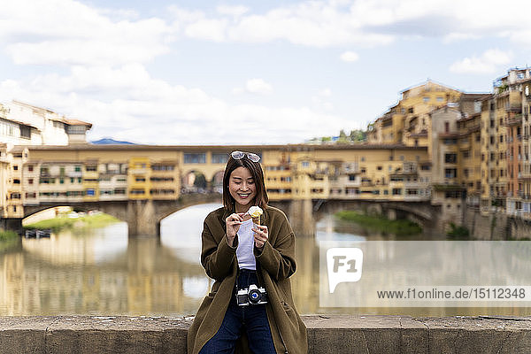 Italy  Florence  young tourist woman eating an ice cream cone at at Ponte Vecchio