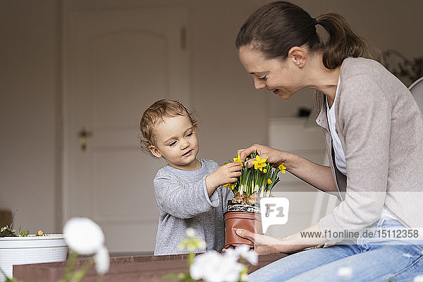 Mutter und Tochter pflanzen gemeinsam Blumen auf dem Balkon