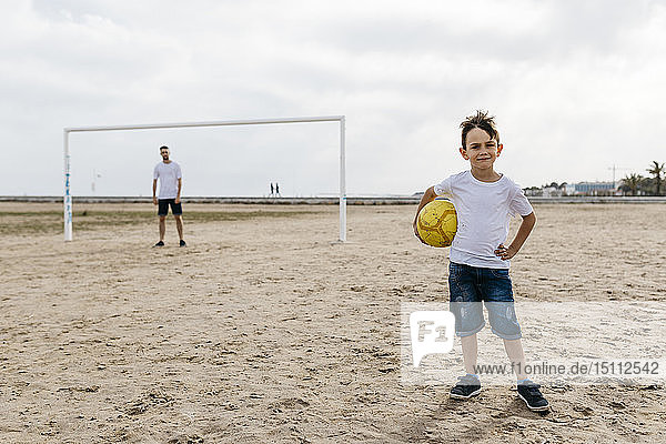 Porträt eines Jungen mit Fussball am Strand