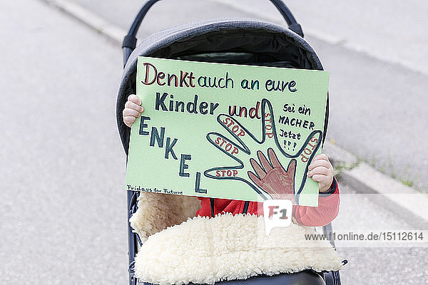 Baby im Kinderwagen mit einem Plakat auf einer Demonstration für Umweltschutz