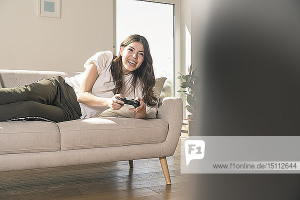 Glückliche junge Frau spielt zu Hause Videospiel