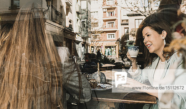 Zwei junge Frauen hinter einer Fensterscheibe in einem Cafe
