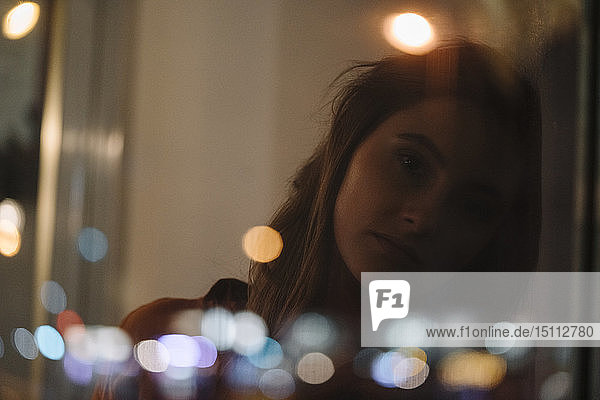 Porträt einer seriösen jungen Frau hinter einer Fensterscheibe