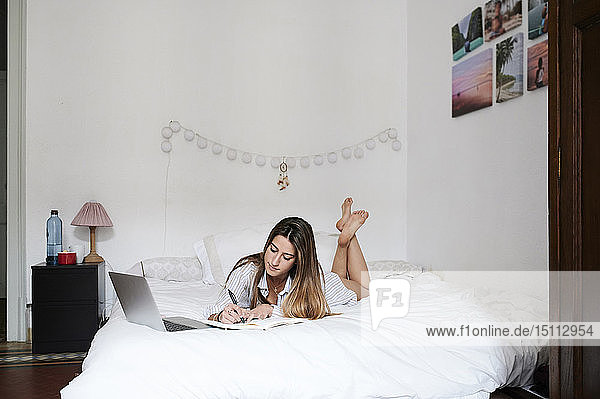 Young woman lying in bed  using laptop