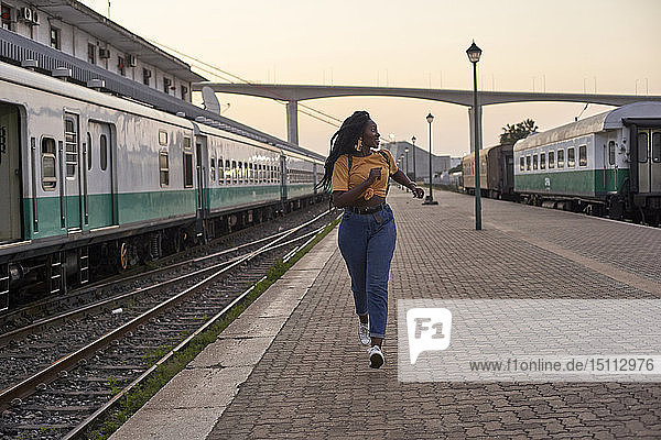 Young woman running on platform at the train station