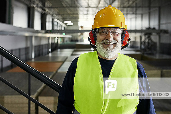 Porträt eines lächelnden reifen Arbeiters in einem Fabriklager
