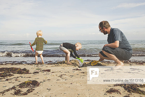 Father with two kids playing on the beach