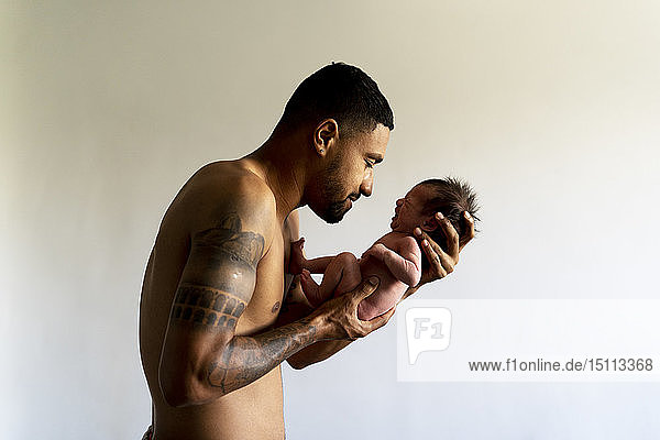 Zärtlicher Vater hält sein weinendes nacktes Neugeborenes