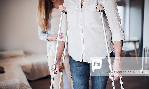 Daughter helping her mother to walk with crutches