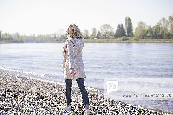 Glückliche reife Frau beim Spaziergang am Flussufer