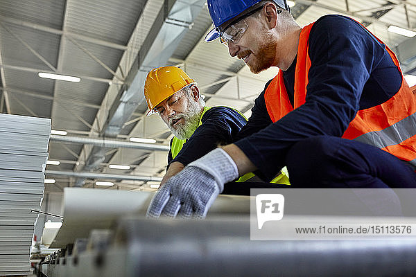 Two men working on plan in factory