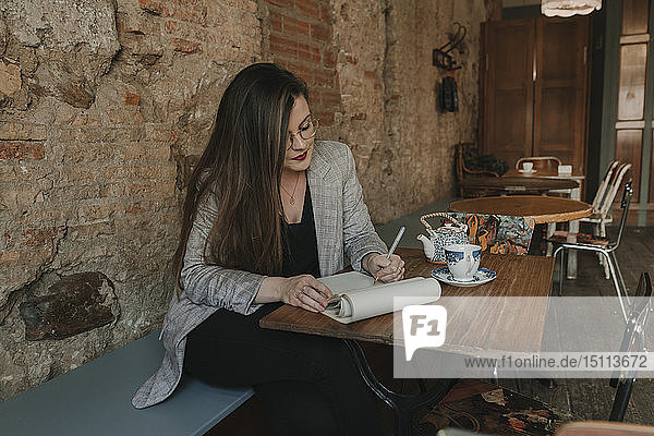 Junge Frau macht Notizen in einem Cafe