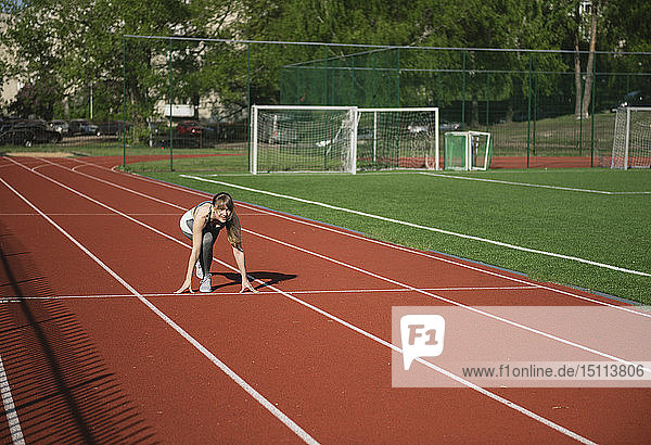 Female runner on tartan track in starting position