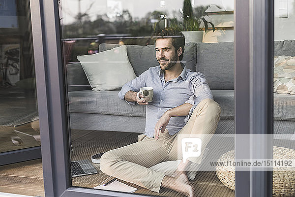 Young man sitting in front of window drinking coffee