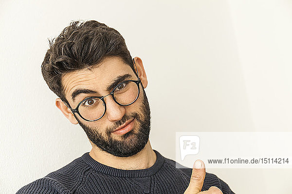 Portrait of doubting young man with beard and glasses