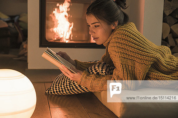 Junge Frau liest zu Hause am Kamin
