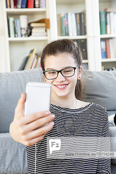 Portrait of smiling girl taking selfie at home