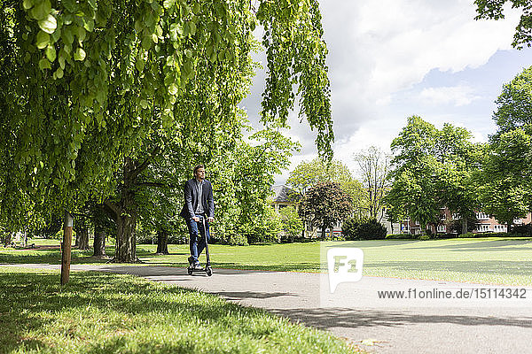 Businessman using E-Scooter in a park