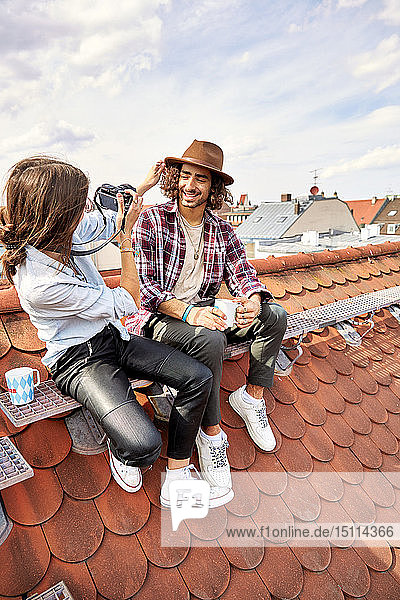 Young couple sitting on rooftop and taking a picture