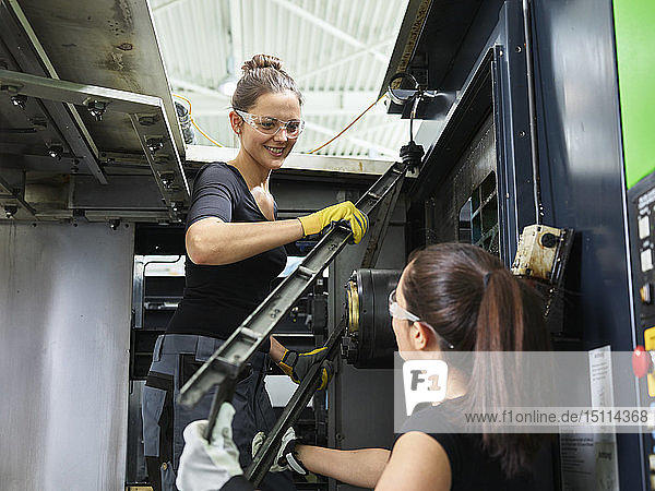 Zwei Frauen arbeiten an einer Maschine. Heben von Stahl