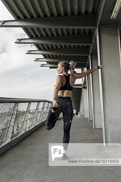 Sporty woman  warming up on a bridge  stretching leg