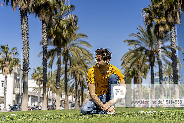 Spain  Barcelona  man on lawn in the city looking around