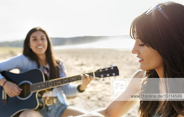 Zwei Frauen mit Gitarre am Strand
