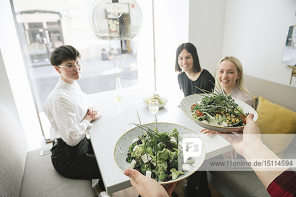 Kellner  der Freunden in einem Restaurant Salat serviert