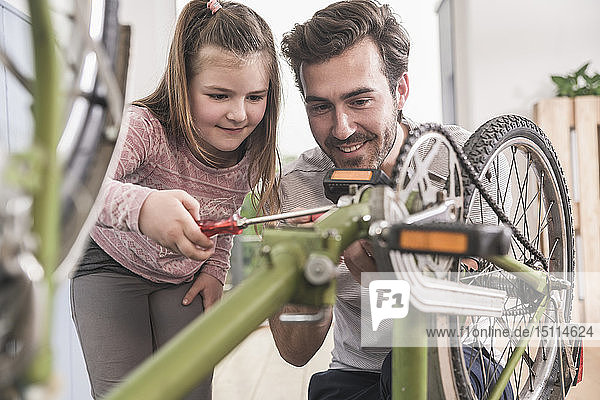 Junger Mann und kleines Mädchen reparieren gemeinsam Fahrrad