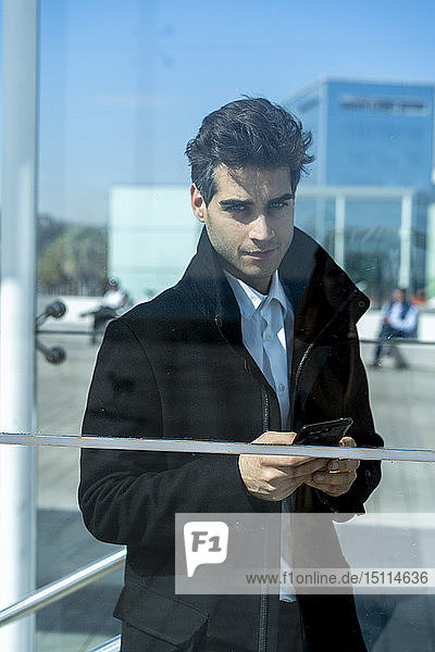 Portrait of confident businessman with cell phone in the city