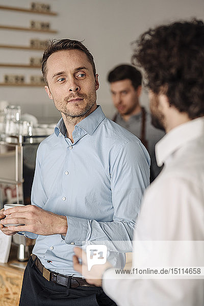Two businessman drinking coffee in a coffee shop  talking