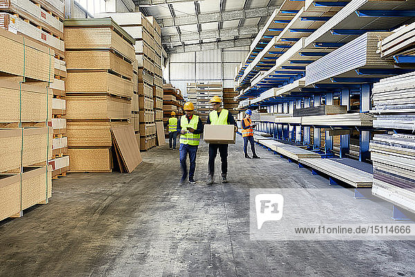 Workers moving and carrying boxes in factory warehouse