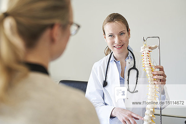 Female doctor explaining spine model to patient in medical practice