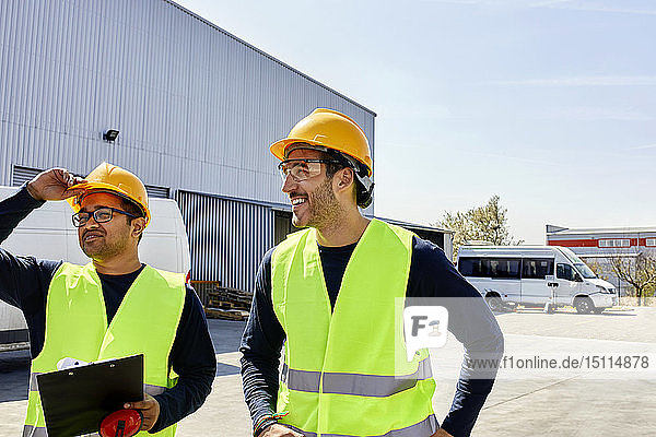 Two workers talking on factory yard