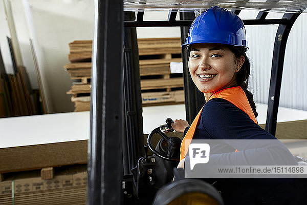 Porträt einer selbstbewussten Arbeitnehmerin auf einem Gabelstapler in der Fabrik