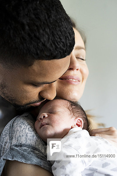 Eltern kuscheln mit schlafendem Neugeborenen