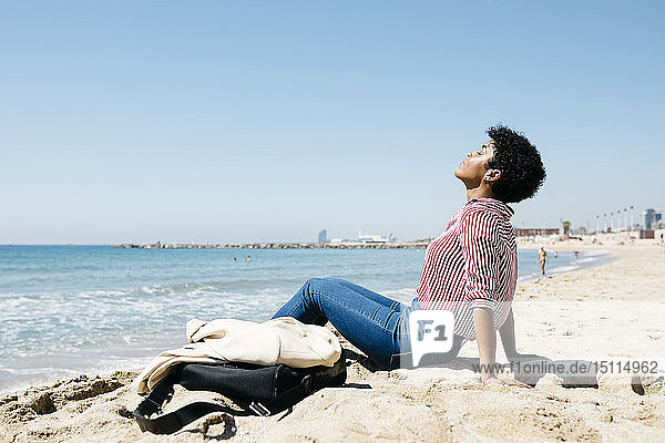 Woman sitting on the beach enjoying the sun after work